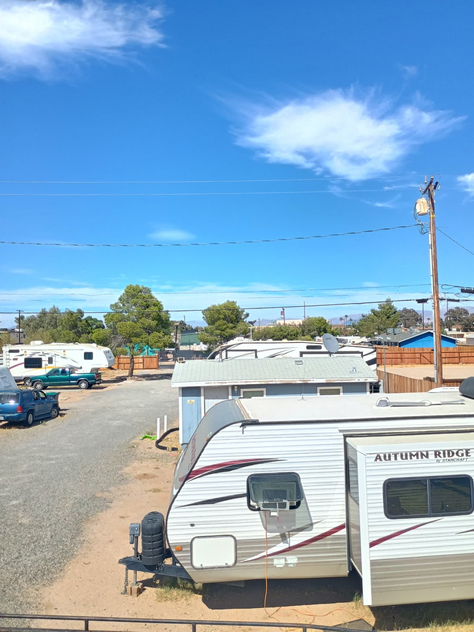 A travel trailer parked at its site beside the gravel lane